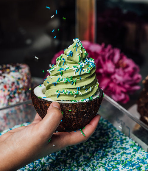 matcha soft serve with blue and white sprinkles served in a fresh coconut.